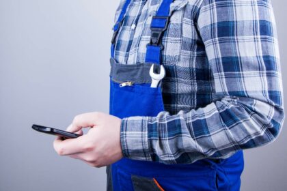 Ein Handwerker hält sein Handy in der Hand
