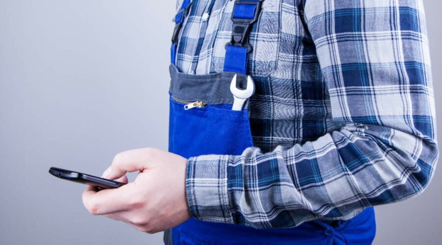 Ein Handwerker hält sein Handy in der Hand