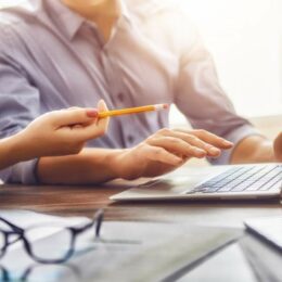 Zwei Personen in einer Besprechung mit Laptop, Stift und Unterlagen