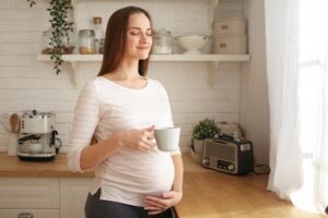 Schwangere Frau genießt eine Tasse Himbeerblaettertee zur Vorbereitung auf die Geburt