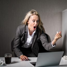 Wuetende Frau ist genervt von Werbung am Arbeitsplatz und schreit ihren Computer an