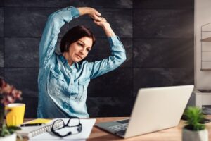 Frau macht Stretchinguebungen am Schreibtisch