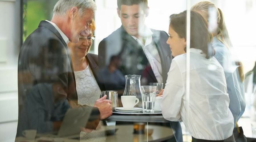 Diverse Mitarbeitende um einen Stehtisch in einer Cafeteria unterhalten sich