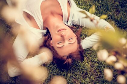 Frau liegt entspannt mit geschlossenen Augen im Gras