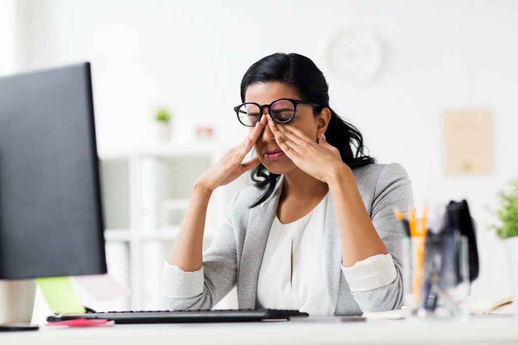 Frau reibt sich angestrengte Augen am Computer