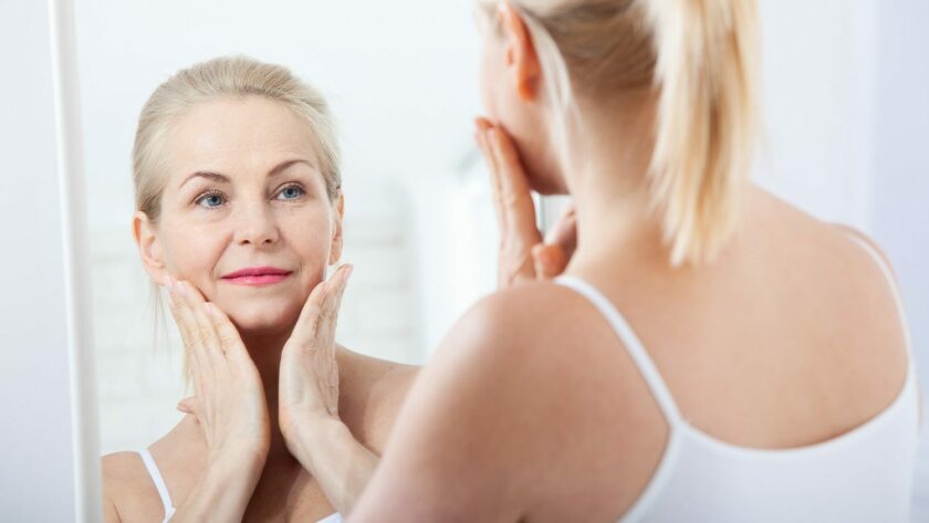 Ältere Frau schaut in den Spiegel und betrachtet ihre Haut Wirkung von Kollagen auf Faltenbildung
