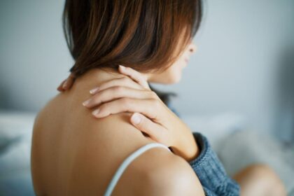 Dunkelhaarige Frau macht Nacken Selbstmassage
