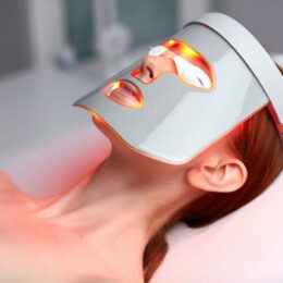 Frau mit LED-Maske liegt bei der Lichttherapie
