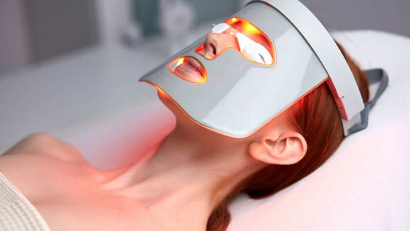 Frau mit LED-Maske liegt bei der Lichttherapie