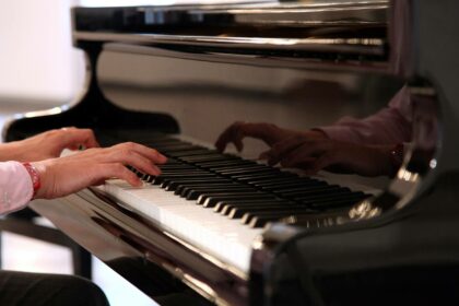 Maennerhaende beim Klavierspielen auf schwarzem Fluegel Detailansicht auf Tastatur