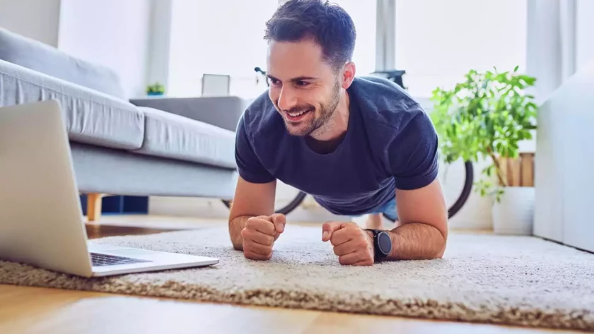 Mann in Plank Position vor dem PC bei Online Fitness Kurs