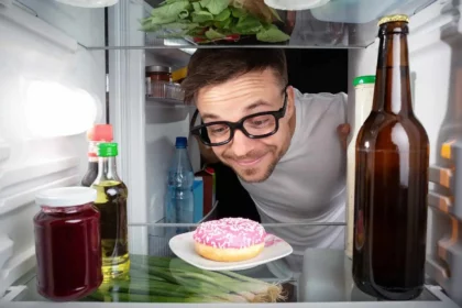 Mann hat Heißhunger und freut sich über donut im kühlschrank